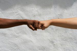 Diverse hands bump fists in solidarity.